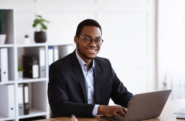 istock Cheerful african businessman working with laptop in office 1299562156