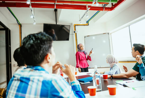 istock Muslim moderator pointing on whiteboard with copy space during seminar with emplyees 1299563253