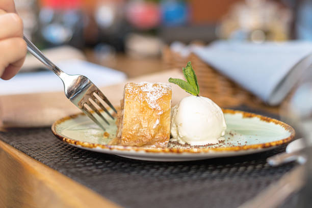 istock Apple strudel with vanilla ice cream and mint. Hands are cut with fork 1299566037