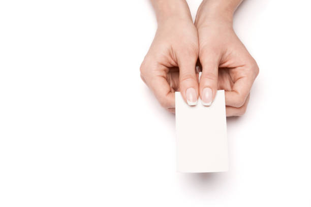 istock Female hand holding a blank business card over white background 1299566199