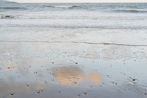 Clouds reflected on the wet sand at the water's edge, Crawfordsburn Beach, County Down, Northern Ireland.