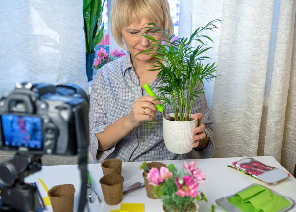 istock Woman sits at home using a camera and recording an online gardening course 1299567416