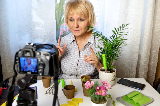 istock Woman sits at home using a camera and recording an online gardening course 1299567419