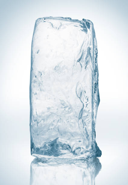 bloc de glace pur et limpide, sur surface blanche avec réflexion. gros morceau de glace. - ice cube clean transparent cold photos et images de collection