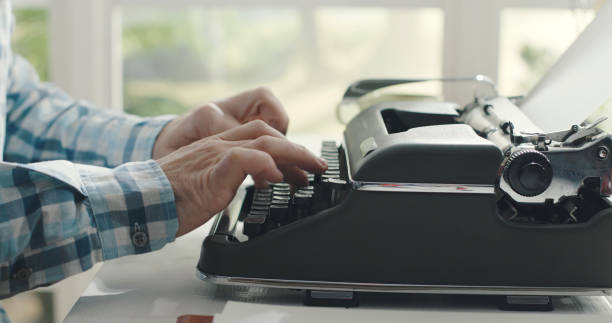 uomo seduto alla scrivania e che digita su una macchina da scrivere - writing typewriter 1950s style retro revival foto e immagini stock