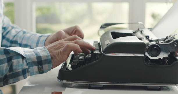 man sitting at desk and typing on a typewriter - writing typewriter 1950s style retro revival imagens e fotografias de stock