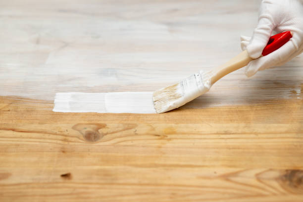 istock A hand in a protective glove with a brush paints a wooden surface 1299571594