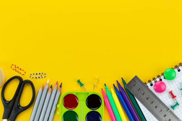 istock school supplies are scattered on a yellow background. 1299572534