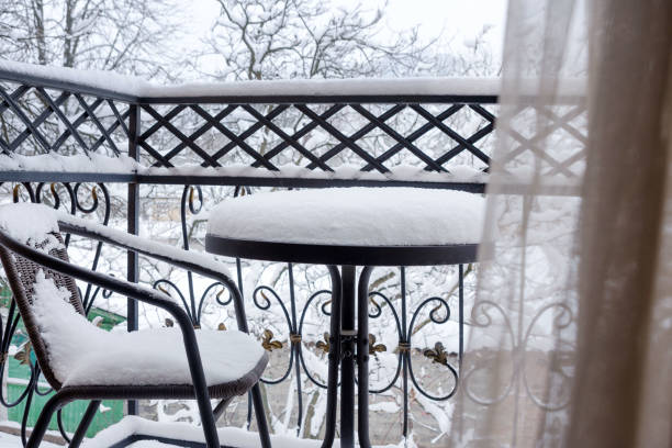 istock The first white fluffy snow on the table and chairs on the wrought-iron balcony. 1299572690