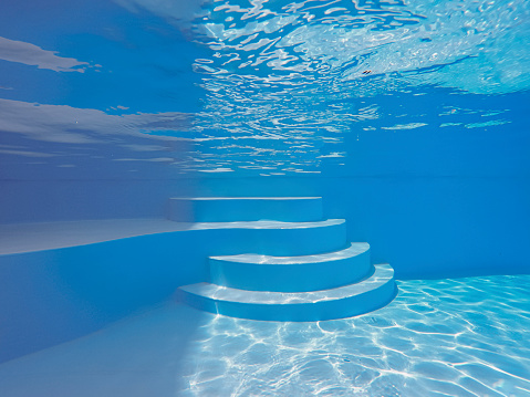 underwater swimming pool with sunlight and water ripple effect on the steps