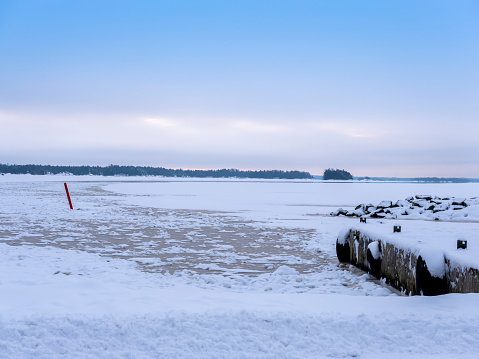 Sipoo / Finland - JANUARY 31, 2021: A beautiful winter scene of a frozen lake with visible shipping lane and a red buoy.