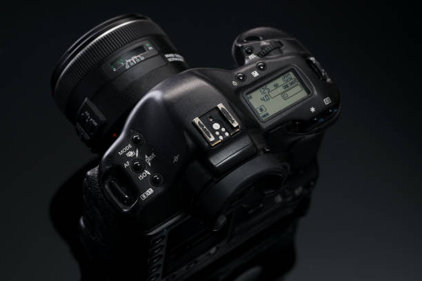 istock A black used professional SLR camera sits on a glass table with a reflection. View from above. 1299579328