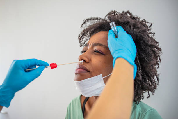 junge ärztin im schutzanzug, die einen tupfertest von einer jungen patientin abnimmt. - dna epidemiology patient science stock-fotos und bilder