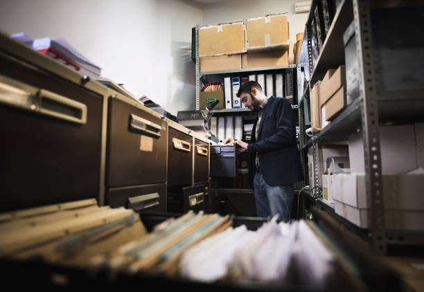 Man in dark file works in office searching old documentation file in basement stock photo