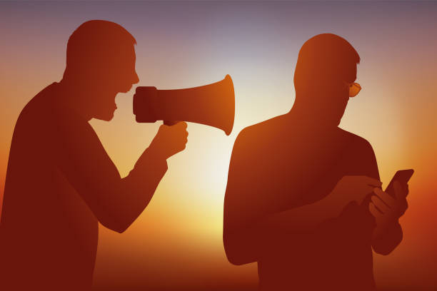 istock Concept of isolation with a man who plays with his smartphone and another who yells at him at the megaphone. 1299581634