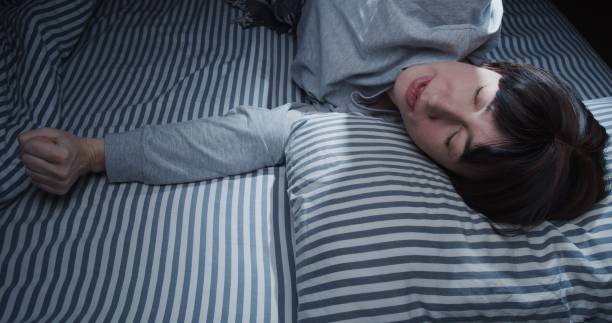 istock Mature woman is waking up and stretching in bed 1299585406