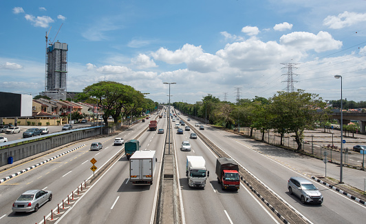 Elevated shot of busy highway with high voltage towers and residential building at Petaling District, Selangor state, Malaysia.