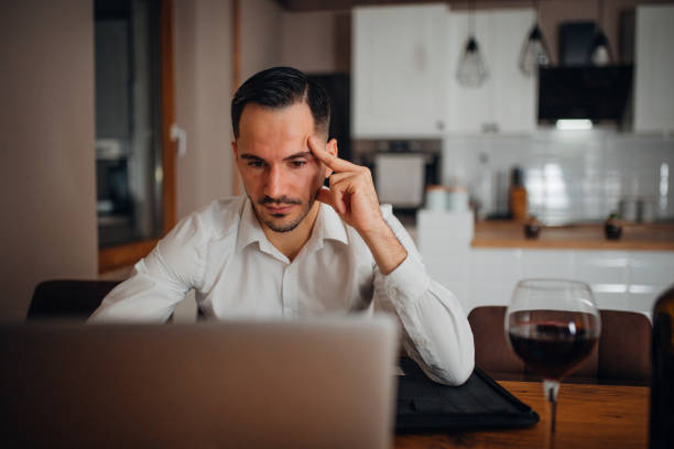 Work from home young businessman works from home in the evening and uses his laptop vollbart stock pictures, royalty-free photos & images