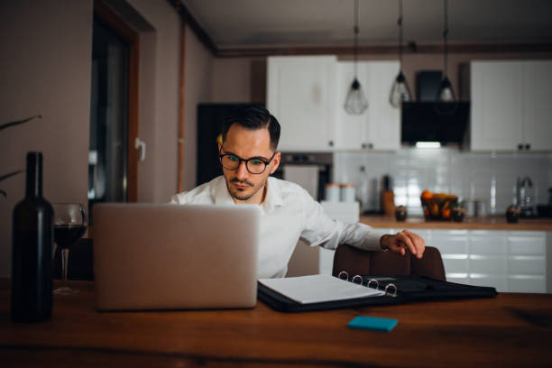 Work from home young businessman works from home in the evening and uses his laptop vollbart stock pictures, royalty-free photos & images