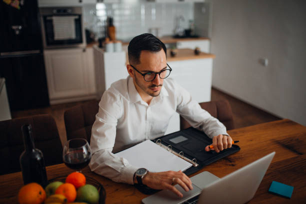 Work from home young businessman works from home in the evening and uses his laptop vollbart stock pictures, royalty-free photos & images
