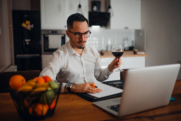 Work from home young businessman works from home in the evening and uses his laptop vollbart stock pictures, royalty-free photos & images