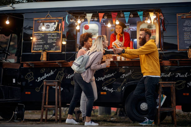 istock multiethnic young people having fun while eating in front of modified truck for mobile fast food service 1299589097