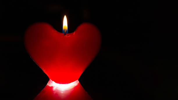 istock A lit red heart shaped candle on dark background. Valentine's day concept 1299589224