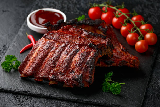istock Grilled pork ribs with bbq sauce and herbs on stone board 1299590177