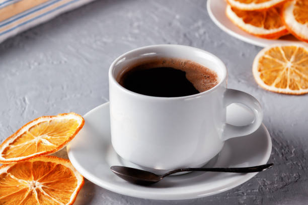 istock Cup of coffee with dried oranges on gray background 1299590524