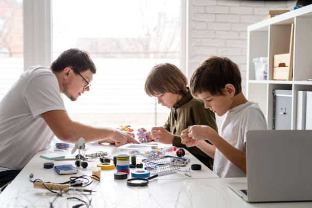 istock Young boys and teacher having fun constructing robot cars at the workshop 1299596481