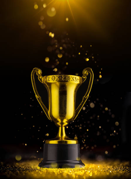 istock Golden trophy on black background in rays of light. 1299597883
