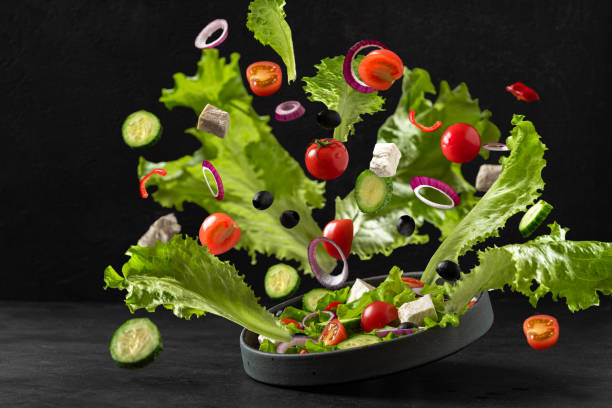 istock Flying Greek salad on black background . Plate with fresh salad and falling ingredients. Vegetarian food. Levitation food 1299597902