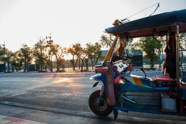 Thai tuk-tuks land on the road at sunset.