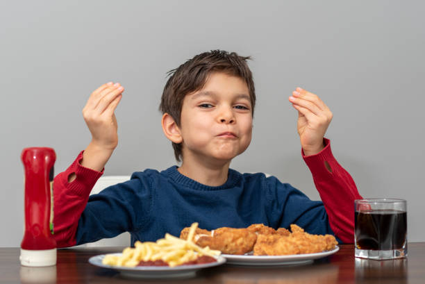 маленький мальчик ест жареную курицу с колой и картофелем фри - deep fried people fried chicken стоковые фото и изображения