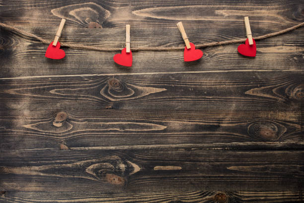 Hearts hanging on rope on wooden background.