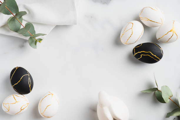 istock Luxury Easter flat lay composition with black and golden eggs, eucalyptus leaves, bunny rabbit, towel on marble table. Happy Easter concept. Top view. 1299603342