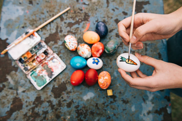 Overhead view on female hand painting easter  eggs on old blue vintage background