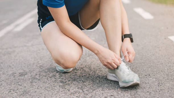istock Young lady running on road closeup on shoe., at time sunset. 1299604211