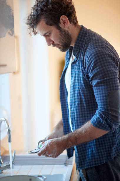 istock Single Caucasian man washing the dishes 1299604497
