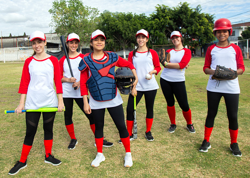 Elementary school-aged athletes, both boys and girls, engage in co-ed little league baseball, supported by their coaches on the vibrant ballfield