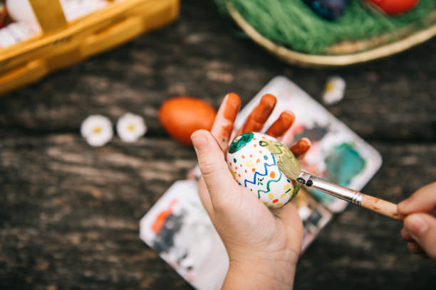 istock little girl painting easter egg with water colors 1299605401