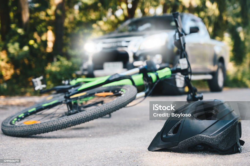 Close-up of a bicycling helmet fallen on the asphalt next to a bicycle after car accident on the road. Conceptual of accident car crash with bicycle on road. Crash Stock Photo