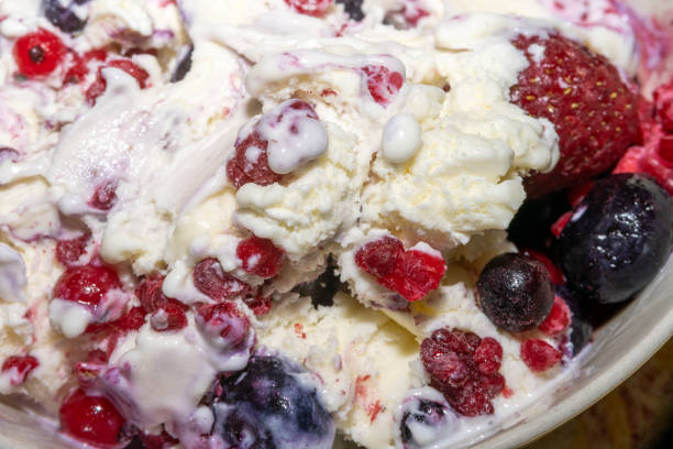 A closeup picture of vanilla ice cream with blue berries and raspberries