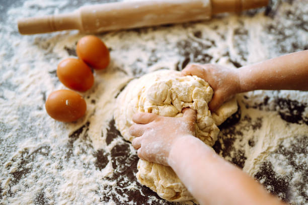 istock Children hands kneading dough on wooden table. Easter baking preparation. Cookies for Christmas. 1299609836