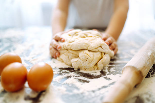 istock Children hands kneading dough on wooden table. Easter baking preparation. Cookies for Christmas. 1299609910