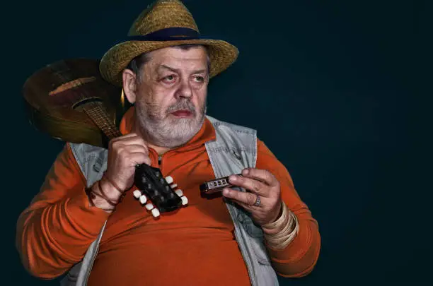 Nice low key portrait of Caucasian senior musician with mandolin and  mouth-organ