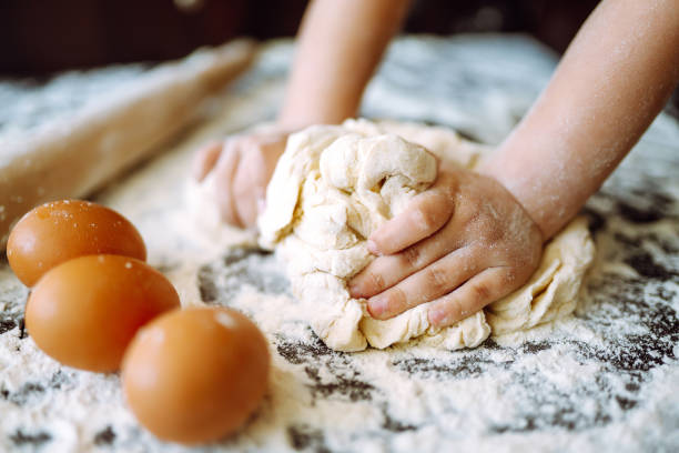 istock Children hands kneading dough on wooden table. Easter baking preparation. Cookies for Christmas. 1299609946