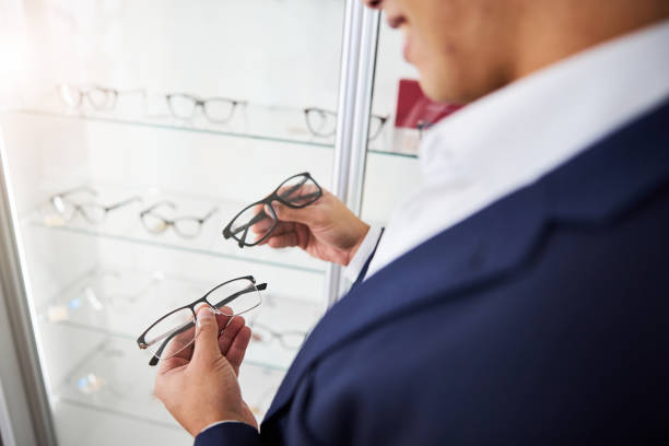 Cropped photo of a smiling young male customer choosing between two new pairs of glasses