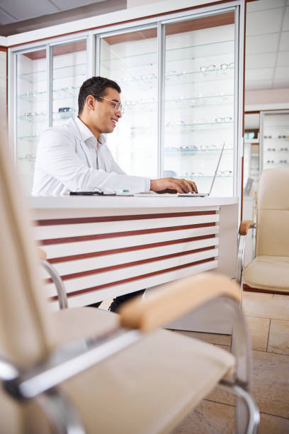 istock Cheerful optician in eyeglasses working on his computer 1299614833