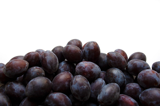 Heap of fresh ripe plums on white background close-up